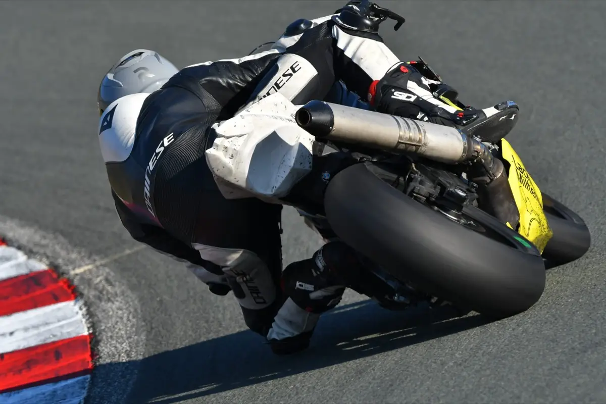 Close-up of a motorcycle racer with knee on the kerb, deep in a corner